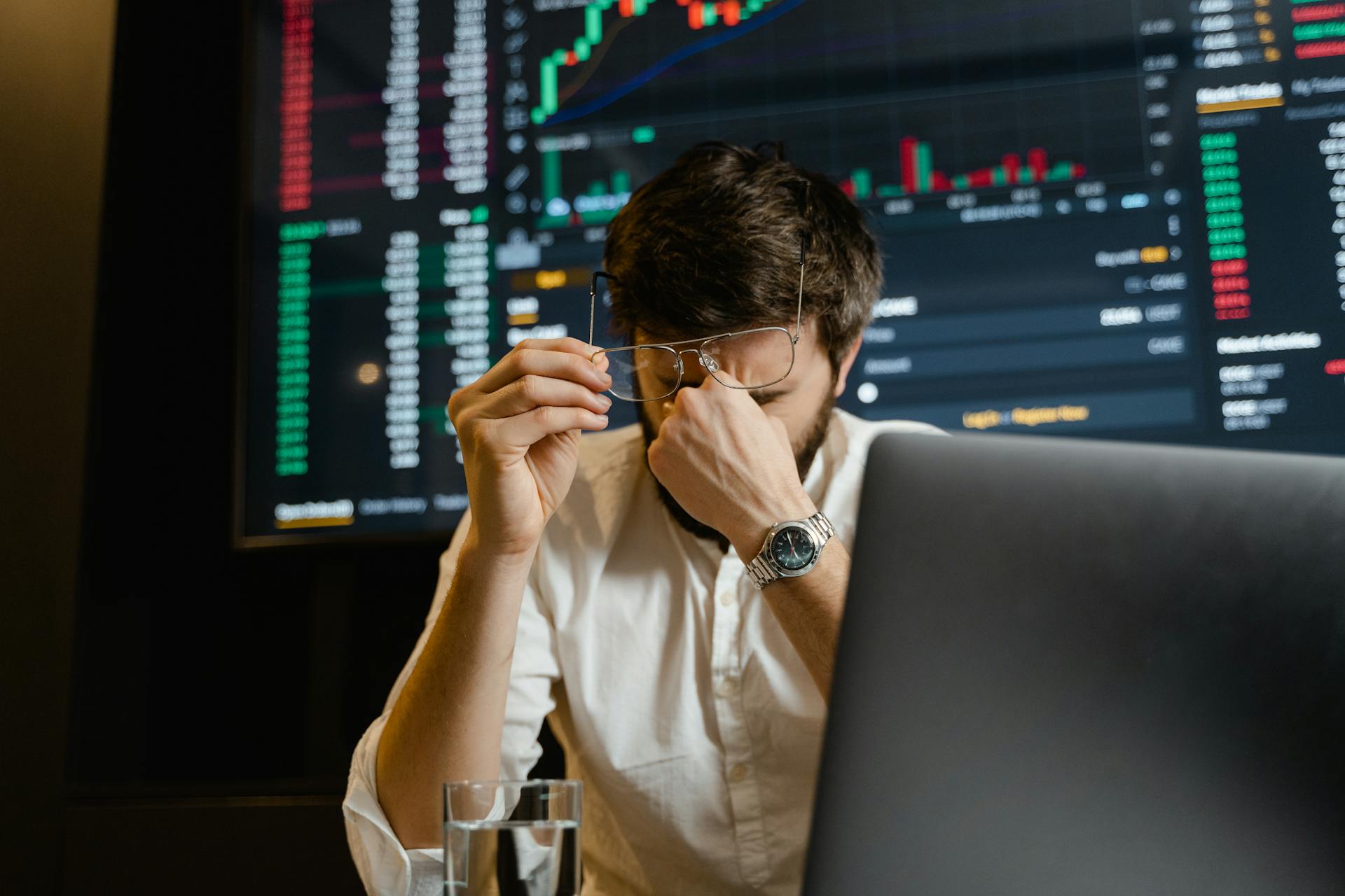 man frustrated at laptop holding head dashboard in background