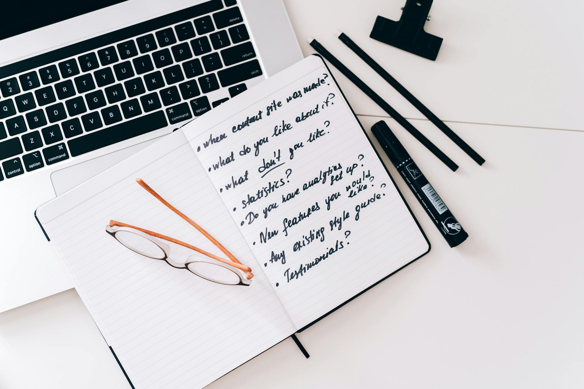 questions in notebook on top of laptop keyboard