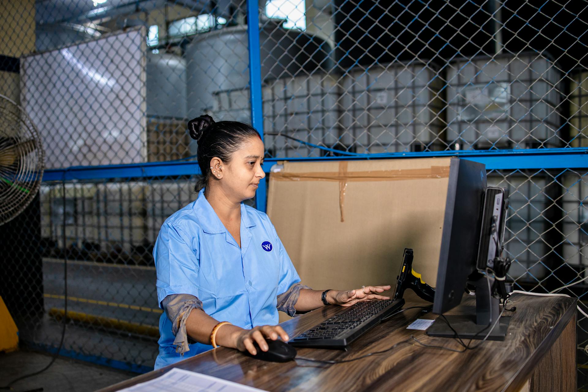 woman at coputer in warehouse with boxes in background automating supply chain logistics